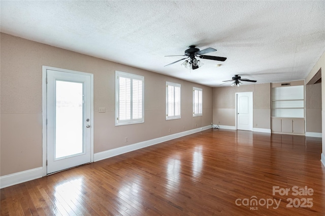 unfurnished living room featuring a textured ceiling, ceiling fan, wood-type flooring, and baseboards