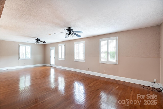 spare room featuring wood finished floors, baseboards, ceiling fan, and a textured ceiling