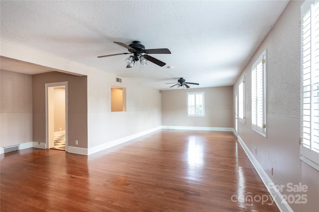 unfurnished room featuring wood finished floors, a ceiling fan, a textured ceiling, and baseboards