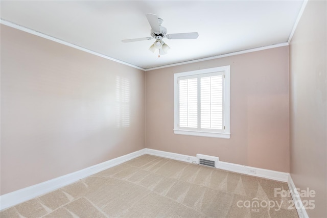 spare room with light colored carpet, crown molding, baseboards, and a ceiling fan