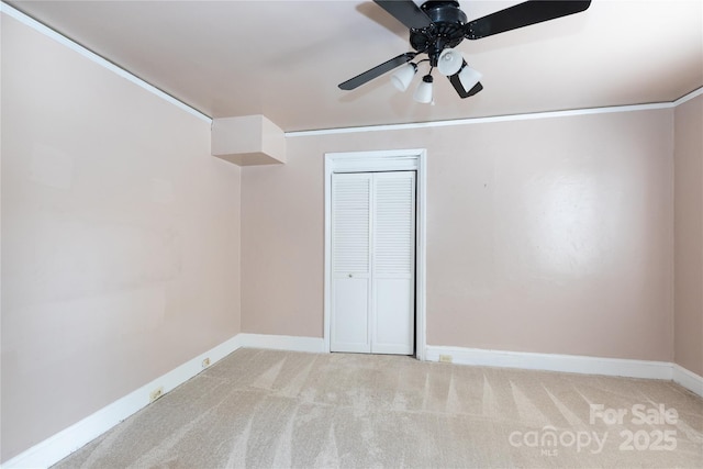 unfurnished bedroom featuring carpet, baseboards, a closet, and ceiling fan