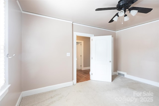 unfurnished bedroom featuring carpet flooring, baseboards, ceiling fan, and crown molding
