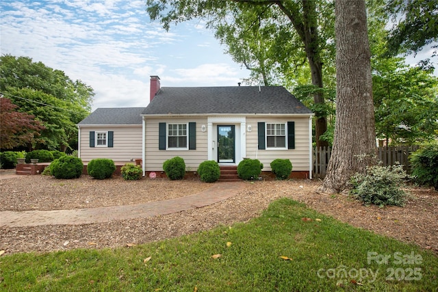 new england style home featuring a chimney and fence