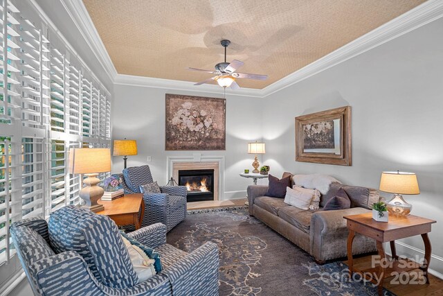 17040 Jetton Rd, Cornelius, NC 28031 - living room with ornamental molding, a textured ceiling, baseboards, a glass covered fireplace, and a ceiling fan
