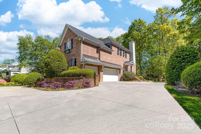 17040 Jetton Rd, Cornelius, NC 28031 - view of side of property with a garage, brick siding, driveway, a chimney, and a standing seam roof