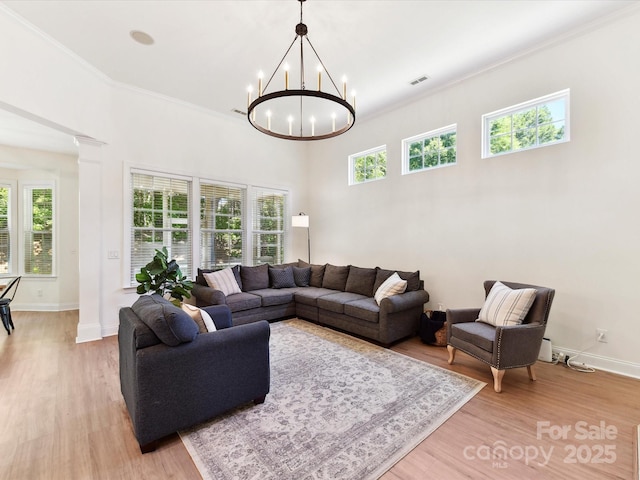 living area featuring visible vents, light wood-style flooring, a wealth of natural light, and decorative columns