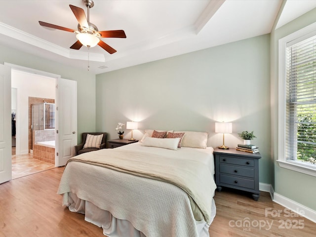 bedroom featuring connected bathroom, wood finished floors, and a raised ceiling
