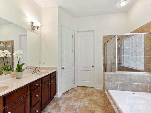 bathroom with double vanity, a shower stall, a sink, and tiled tub