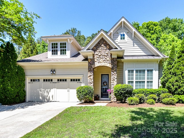 view of front of house featuring a standing seam roof, a front lawn, concrete driveway, an attached garage, and stone siding