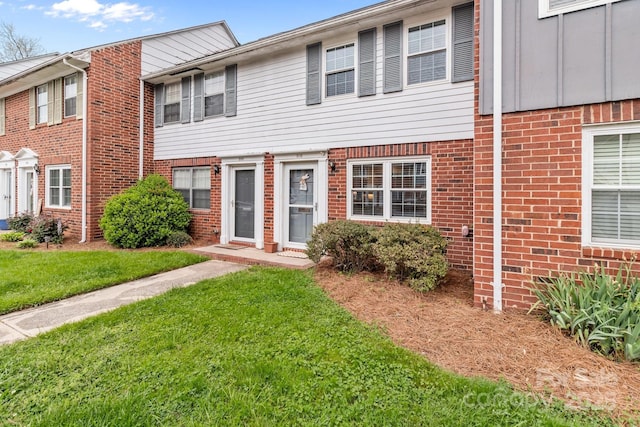 view of property with a front yard and brick siding