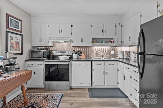 kitchen with white cabinetry, dark countertops, under cabinet range hood, light wood-style floors, and stainless steel appliances