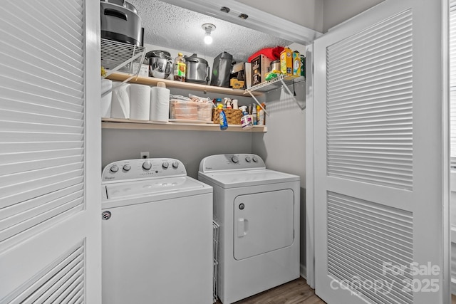 laundry room featuring a textured ceiling, laundry area, washing machine and clothes dryer, and wood finished floors