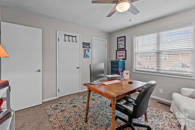 office space with carpet, a textured ceiling, baseboards, and ceiling fan