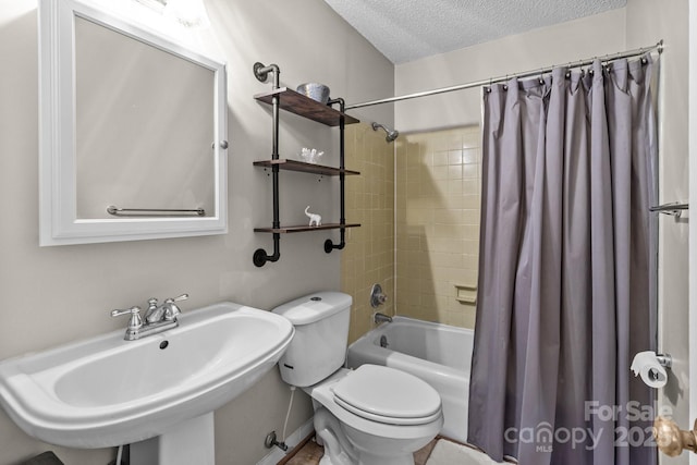 full bathroom with a sink, toilet, shower / bath combo with shower curtain, and a textured ceiling