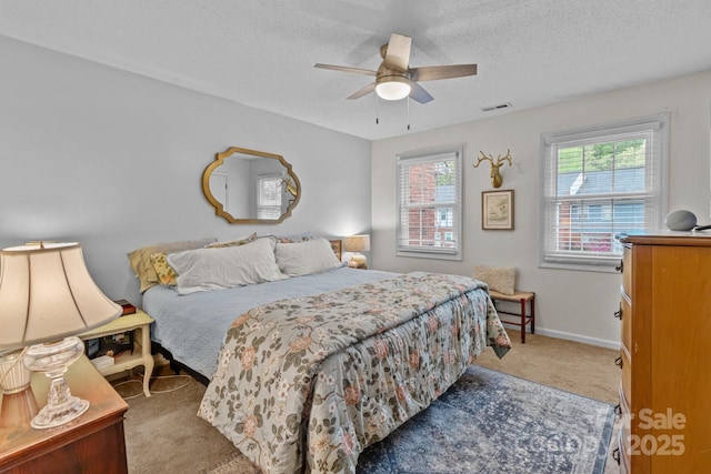 carpeted bedroom featuring visible vents, baseboards, a ceiling fan, and a textured ceiling