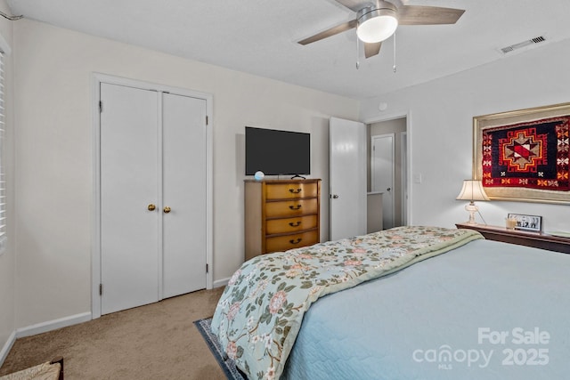 bedroom with a closet, baseboards, visible vents, ceiling fan, and carpet