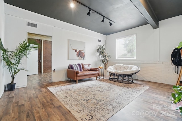 living area with wood finished floors, track lighting, and visible vents