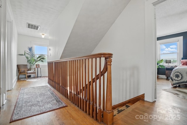 stairway with baseboards, wood finished floors, and visible vents