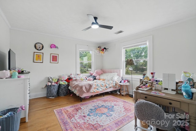 bedroom featuring light wood-style floors, ceiling fan, visible vents, and ornamental molding