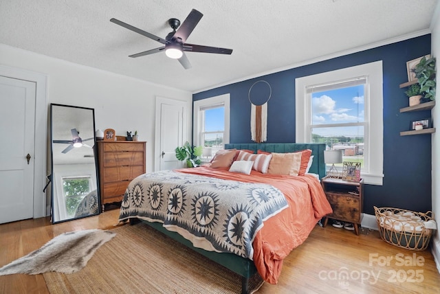 bedroom featuring wood finished floors, a textured ceiling, ceiling fan, and multiple windows