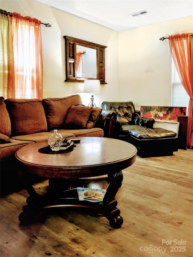 living area with visible vents, plenty of natural light, and wood finished floors