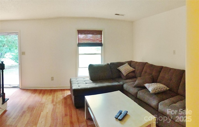 living room featuring baseboards, light wood finished floors, and visible vents