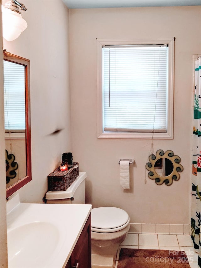 bathroom featuring toilet, plenty of natural light, tile patterned flooring, and vanity