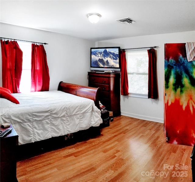 bedroom with visible vents, baseboards, and wood finished floors