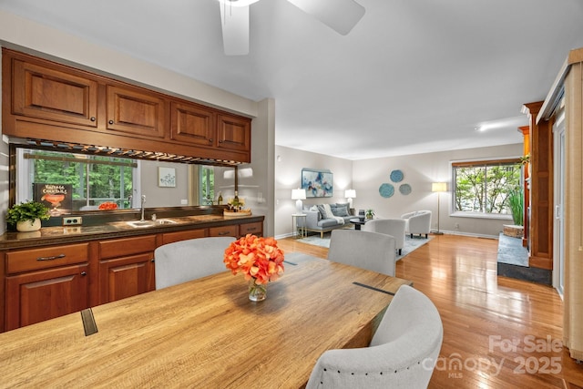 dining area featuring baseboards, ceiling fan, and light wood-type flooring