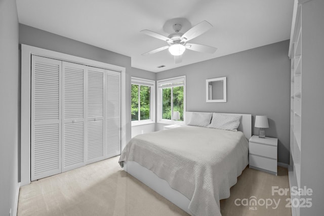 carpeted bedroom featuring ceiling fan and a closet