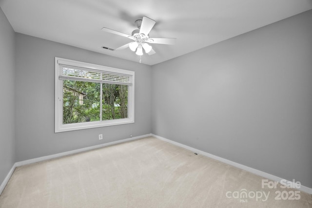 empty room with carpet flooring, a ceiling fan, baseboards, and visible vents