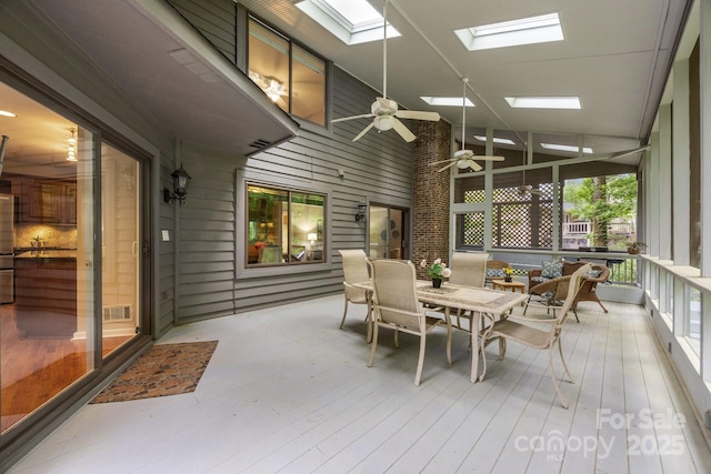 sunroom / solarium featuring outdoor dining area, a ceiling fan, a skylight, and visible vents