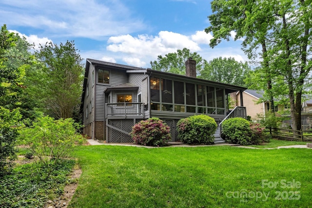 rear view of house with a sunroom, fence, a yard, and a chimney