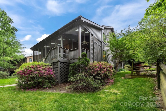 view of side of home featuring a lawn, ceiling fan, and a sunroom