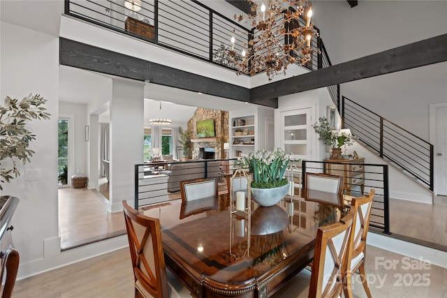 4039 5th St NW, Hickory, NC 28601 - dining space featuring a chandelier, baseboards, wood finished floors, a towering ceiling, and stairs