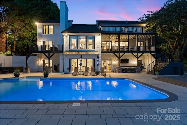 4039 5th St NW, Hickory, NC 28601 - back of house at dusk with a balcony, a patio, stairway, and an outdoor pool