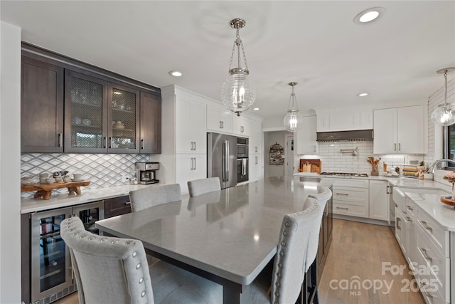4039 5th St NW, Hickory, NC 28601 - kitchen featuring beverage cooler, appliances with stainless steel finishes, a sink, decorative backsplash, and under cabinet range hood