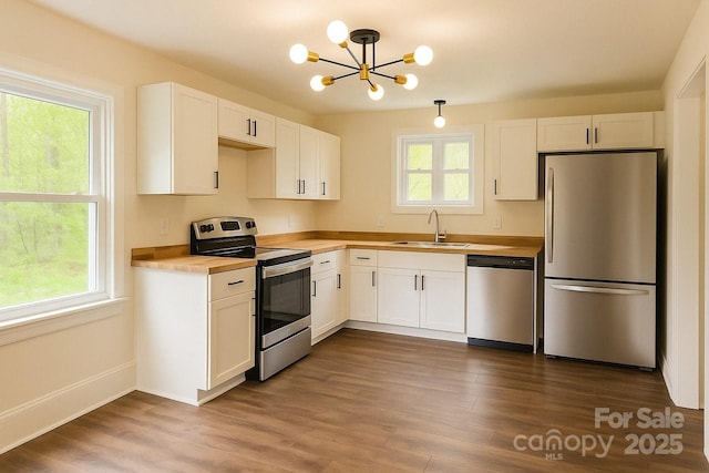 kitchen featuring white cabinets, a chandelier, a sink, stainless steel appliances, and butcher block countertops