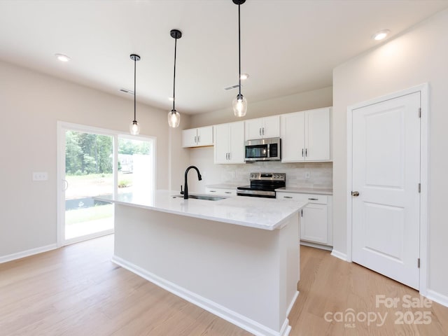 2021 Endeavor Run, Charlotte, NC 28269 - kitchen with stainless steel appliances, a sink, light wood-type flooring, backsplash, and white cabinets