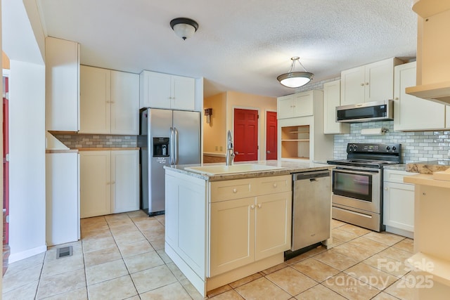 kitchen featuring a sink, light countertops, stainless steel appliances, backsplash, and light tile patterned flooring