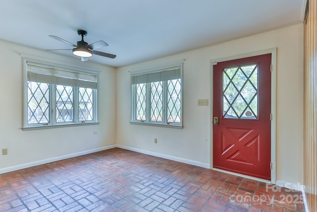 foyer entrance featuring brick floor, ceiling fan, and baseboards