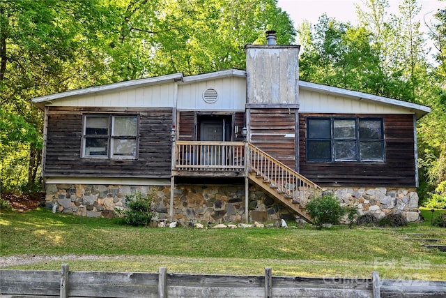 view of front of home featuring a chimney, fence, stairs, and a front yard