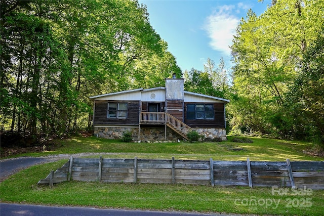 view of front of house with a chimney, a front lawn, fence, and stairs