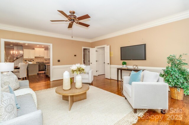 1233 Weymouth Ln, Charlotte, NC 28270 - living room featuring a wainscoted wall, ornamental molding, ceiling fan with notable chandelier, and wood finished floors