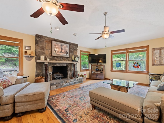218 Red Oak Dr, Maggie Valley, NC 28751 - living room featuring a ceiling fan, wood finished floors, healthy amount of natural light, and a stone fireplace