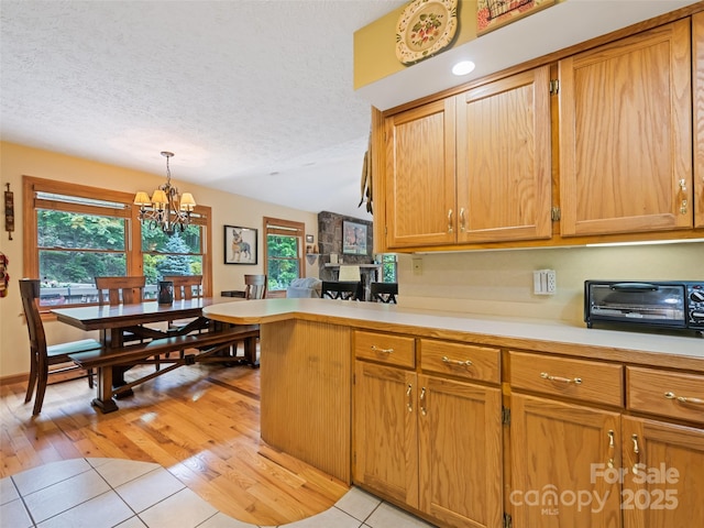 218 Red Oak Dr, Maggie Valley, NC 28751 - kitchen with a textured ceiling, light countertops, a chandelier, light tile patterned floors, and healthy amount of natural light