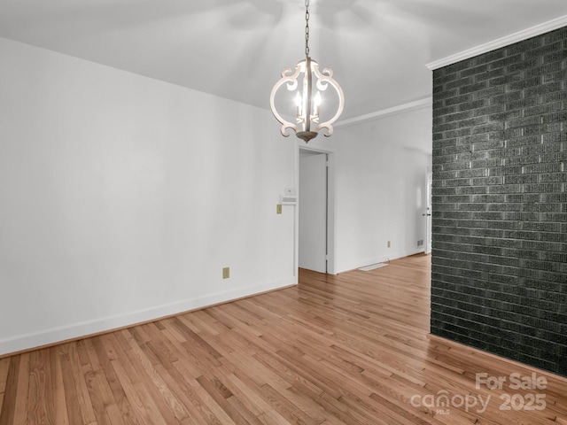 unfurnished room featuring a chandelier, light wood-style flooring, and baseboards