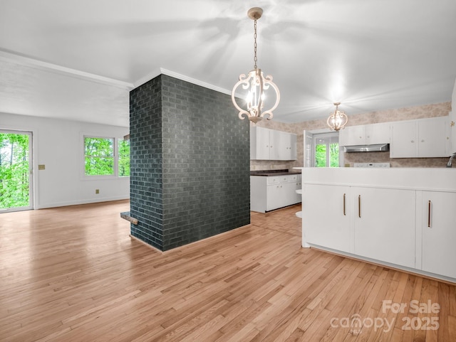 kitchen featuring under cabinet range hood, a chandelier, healthy amount of natural light, and light wood-style floors