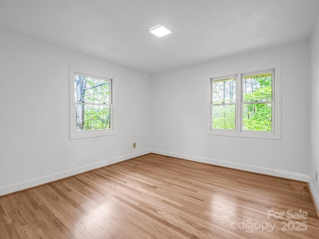 unfurnished room with plenty of natural light, baseboards, and light wood finished floors