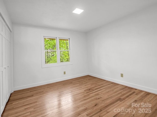 unfurnished bedroom featuring a closet, light wood finished floors, and baseboards